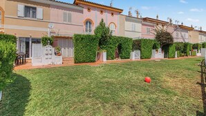 A row of pastel-colored houses with a well-maintained lawn and hedges.