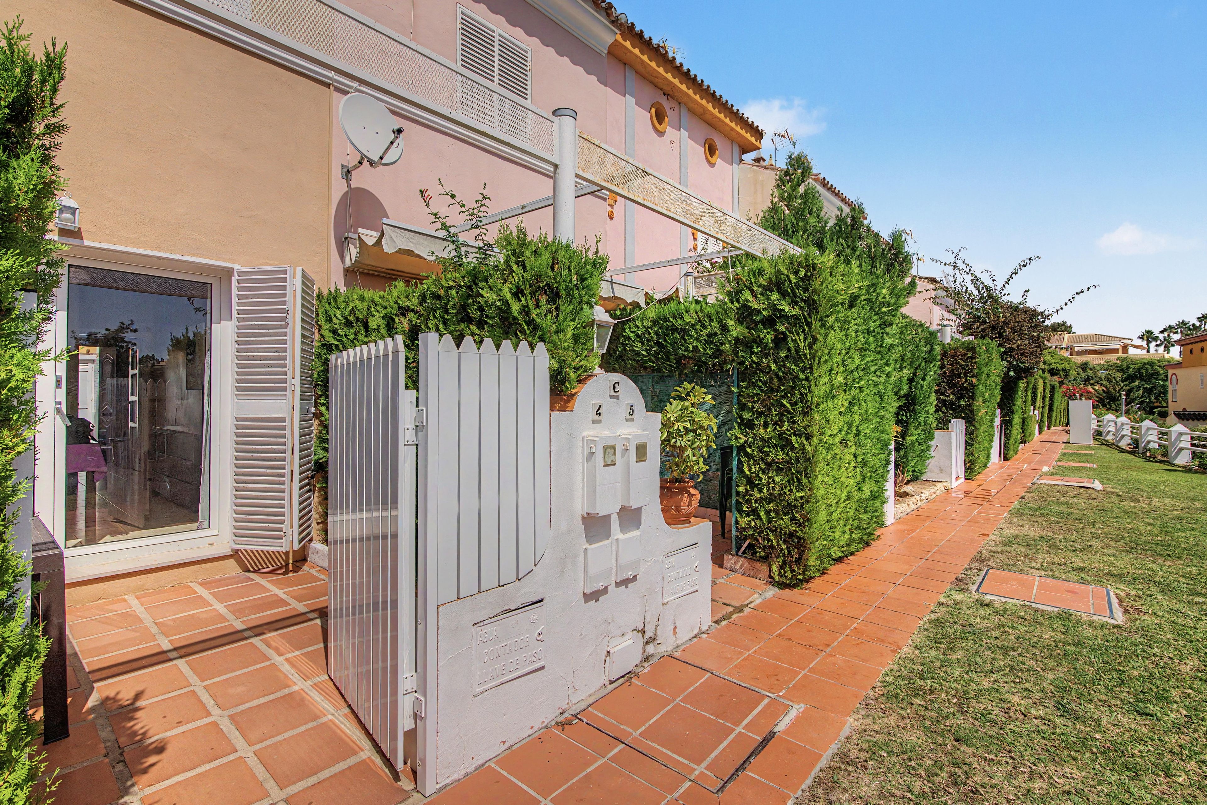 Una propiedad residencial con un patio empedrado, una verja blanca y una antena parabólica.
