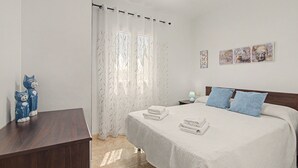 A bedroom with a bed, a nightstand, a lamp, and a wall with artwork.