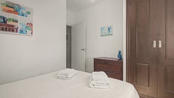Un dormitorio con cama, cómoda, armario y un cuadro en la pared.