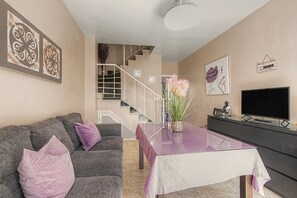 A living room with a sofa, a coffee table, a TV, and a staircase. - Apartment 'Mirador Del Golf' with Shared Pool, Private Terrace and Wi-Fi (Islantilla)