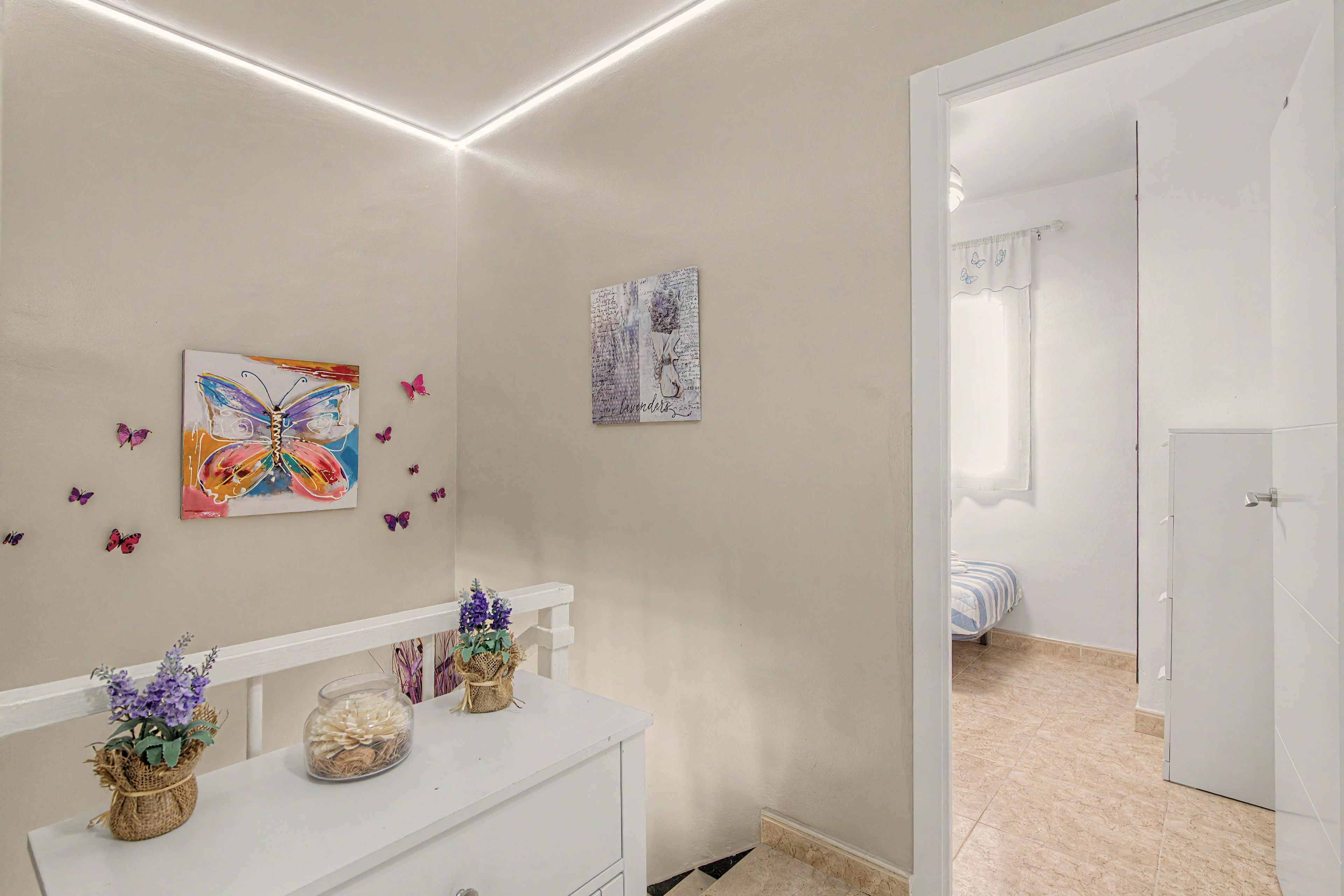 Ein Zimmer mit einem weißen Schminktisch, einem Gemälde und einem gerahmten Bild an der Wand.