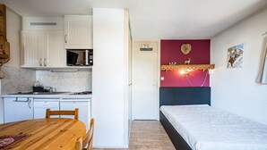 Ein gemütlicher Raum mit Küchenzeile, einem Bett, einem Esstisch und einem 'Welcome'-Schild.