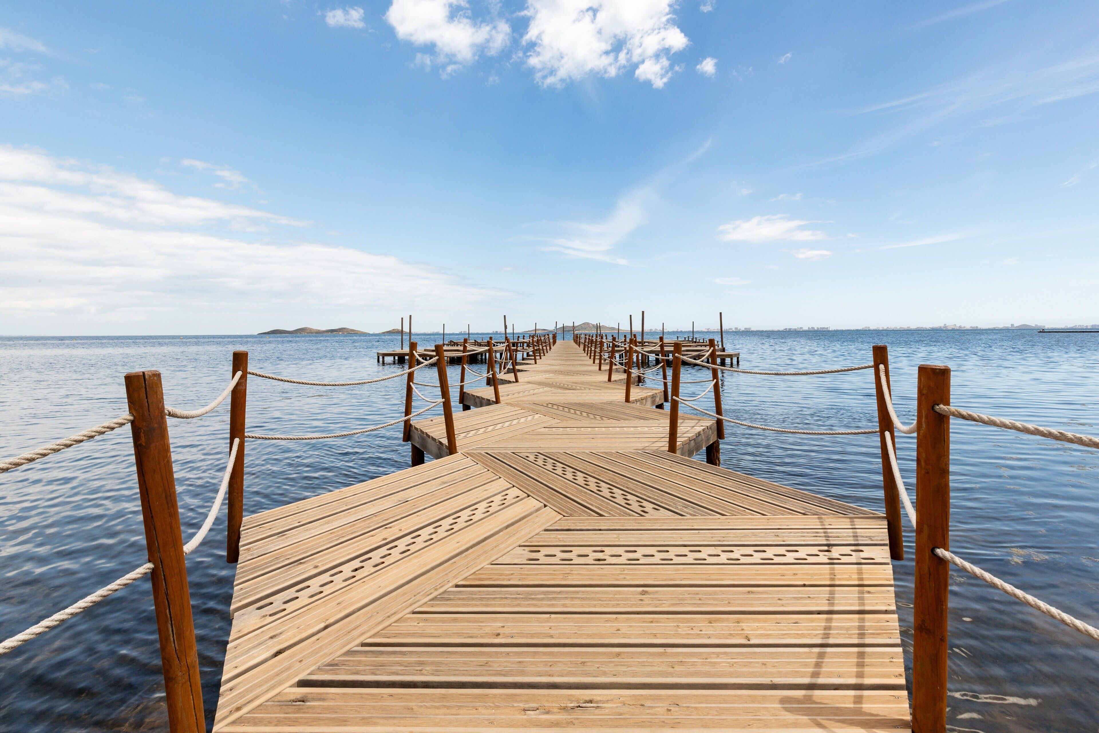 Un muelle de madera que se adentra en aguas tranquilas bajo un cielo despejado.