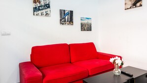 Un sofá rojo, un florero con flores y tres cuadros en la pared.