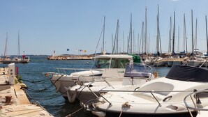 A marina with several boats docked, a rocky shoreline, and a clear sky.