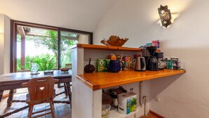 A kitchen with a wooden table, chairs, and various kitchen items.