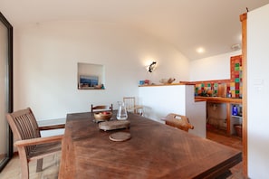 Un'area pranzo con un tavolo di legno, sedie, una brocca e una ciotola.