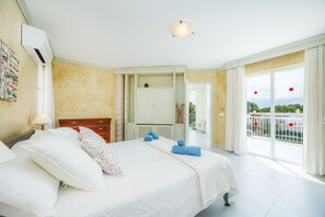 Habitación de hotel con cama, armario, baño y balcón con vistas.