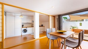 A modern kitchen with white cabinets, a washing machine, and a dining area with a table and chairs. - Apartment 'Casa Azahar' with Private Pool, Wi-Fi, and Air Conditioning (Níjar)