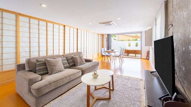 A modern living room with a sofa, a coffee table, a flat-screen TV, and a view of an outdoor patio. - Apartment 'Casa Azahar' with Private Pool, Wi-Fi, and Air Conditioning (Níjar)