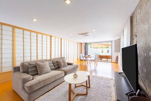 A modern living room with a sofa, a coffee table, a flat-screen TV, and a view of an outdoor patio. - Apartment 'Casa Azahar' with Private Pool, Wi-Fi, and Air Conditioning (Níjar)