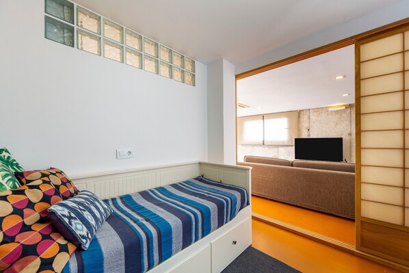 Un dormitorio con cama, televisión, sofá y puerta corrediza.