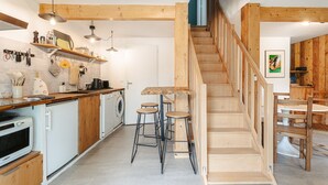 Een keuken met houten balken, een trap en barstoelen.