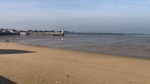 A beach with a lighthouse, calm water, and a distant shoreline with buildings. - Gabae - Les Volets Gris: Comfortable Holiday Home with Wi-Fi and Remote Work Space (Puyravault)