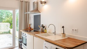 A modern kitchen with a wooden countertop, a built-in oven, a dishwasher, a sink, and a range hood. - Gabae - Les Volets Gris: Comfortable Holiday Home with Wi-Fi and Remote Work Space (Puyravault)