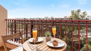 A balcony with a table set for breakfast, including croissants and orange juice, overlooking a cityscape. - Apartment 'Top Floor Fuengirola Park' with Private Terrace, Wi-Fi and Air Conditioning (Fuengirola)