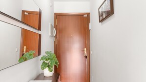 A hallway with a wooden door, a mirror, a potted plant, and a framed picture on the wall. - Apartment 'Top Floor Fuengirola Park' with Private Terrace, Wi-Fi and Air Conditioning (Fuengirola)