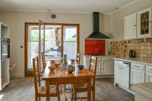 A kitchen with a wooden dining table, white cabinets, and a red backsplash. - Holiday Home 'Le Moulin De Bayard' with Mountain View, Private Terrace & Wi-Fi (Pontcharra)
