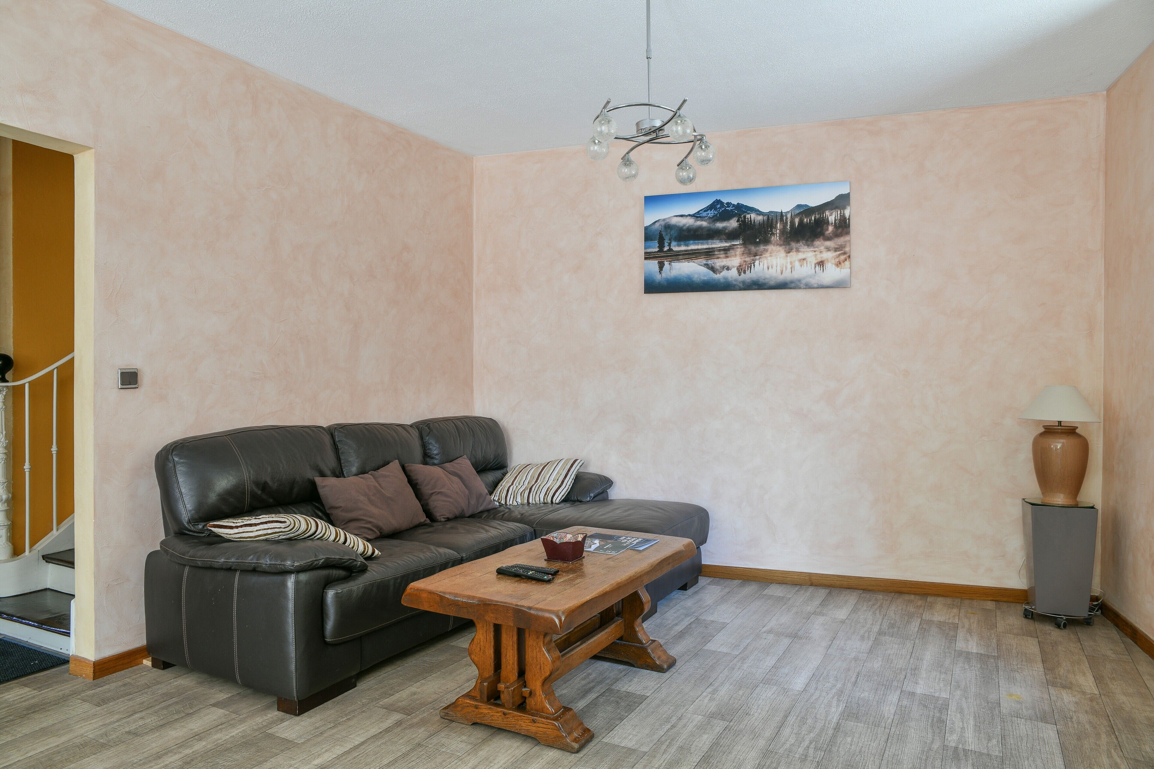 Ett vardagsrum med en soffa, ett soffbord, en lampa och en tavla på väggen.