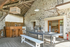 An outdoor dining area with a stone wall, wooden bar, and a grill. - Holiday Home 'Le Moulin De Bayard' with Mountain View, Private Terrace & Wi-Fi (Pontcharra)