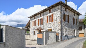 Un bâtiment en pierre doté de nombreuses fenêtres et d’une porte, entouré d’une zone pavée et d’une clôture.