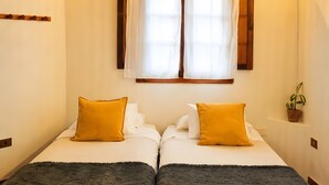 A room with two beds, a hanging light fixture, a window with curtains, and a small plant. - Vacation 'Casa Guimar' with Sea View, Wi-Fi and Air Conditioning (Tanque)