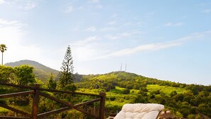 Two sun loungers with white cushions on a wooden deck overlooking a lush green landscape with hills and a clear sky. - Vacation 'Casa Guimar' with Sea View, Wi-Fi and Air Conditioning (Tanque)