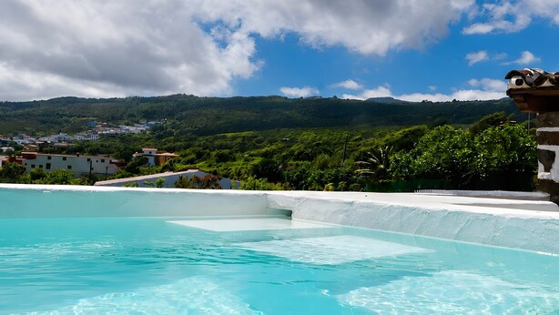 A swimming pool with clear water, surrounded by greenery and buildings in the background. - Vacation 'Casa Guimar' with Sea View, Wi-Fi and Air Conditioning (Tanque)