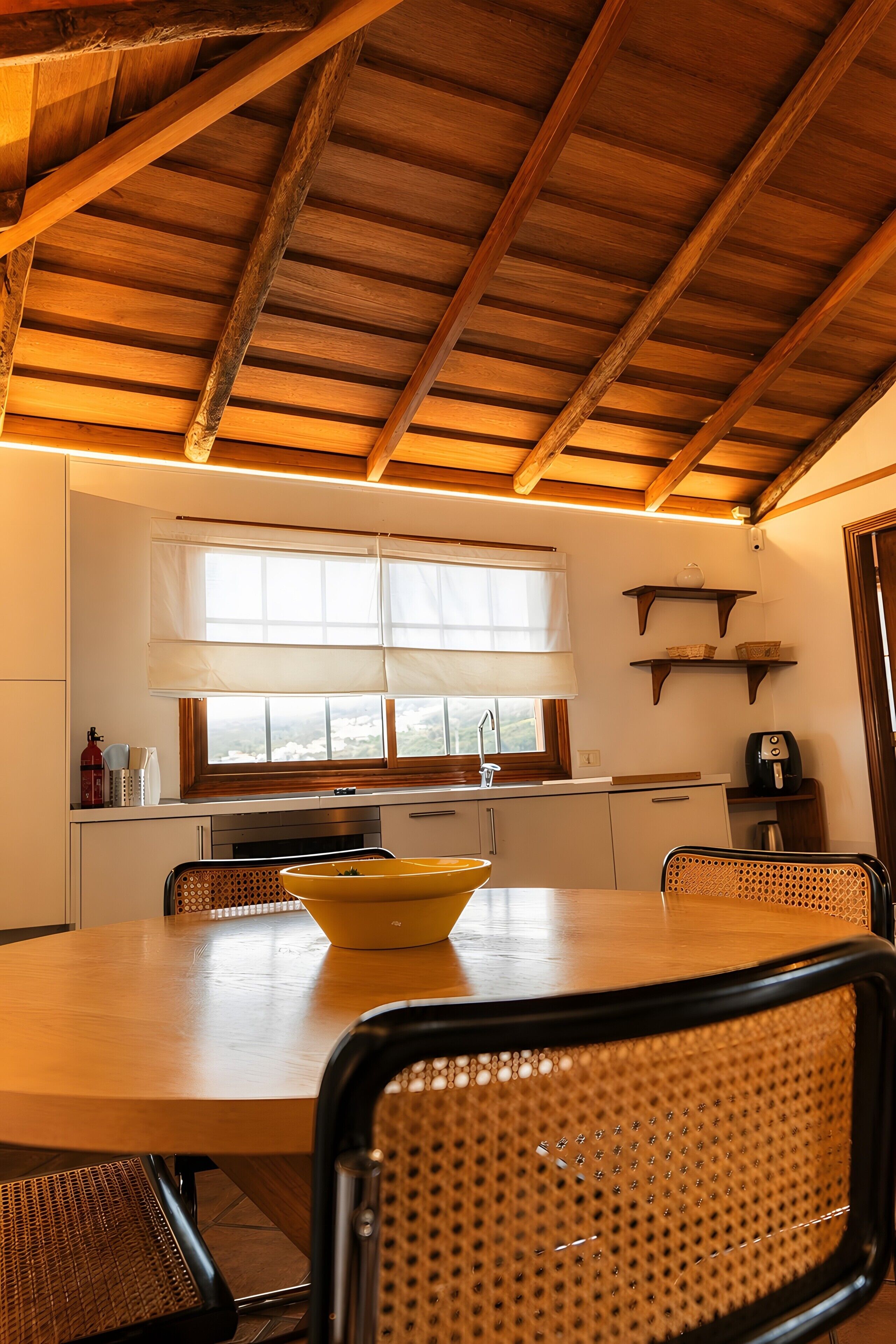 A kitchen with wooden beams, a window with blinds, a sink, and a stove.