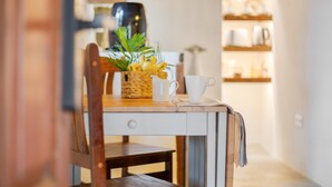 A kitchen with a wooden table, a white pitcher, a white cup, and a plant on the table.