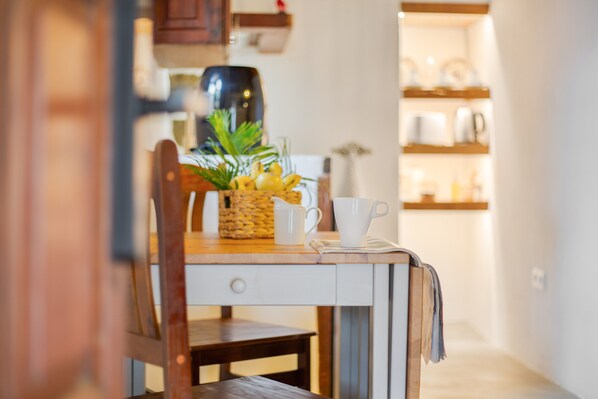 A kitchen with a wooden table, a white pitcher, a white cup, and a plant on the table.