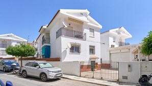 A two-story residential building with a balcony, satellite dish, and a gated entrance.