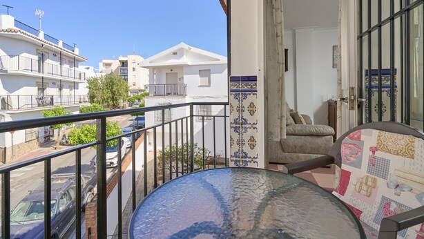 A balcony with a view of neighboring buildings, a table, and a chair.