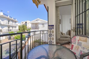 A balcony with a view of neighboring buildings, a table, and a chair.
