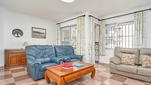 A living room with a blue sofa, a wooden coffee table, a beige sofa, and a checkered floor.