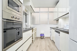 A modern kitchen with a built-in washer, oven, and dishwasher.