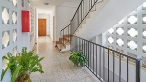 Un pasillo con una escalera, una puerta de madera y una planta en maceta.
