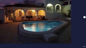 Ein Schwimmbad mit einer Terrassenanlage, einem überdachten Sitzbereich und einer Treppe zu einer erhöhten Ebene.