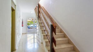 A staircase with a wooden handrail leading to an upper floor, a white door on the left, and a fire extinguisher mounted on the wall. - Vacation 'Candelaria 1' with Sea View, Wi-Fi and Air Conditioning (Candelaria)