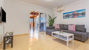 A living room with a grey sofa, a white coffee table, a TV on a stand, and a painting on the wall. - Vacation 'Candelaria 1' with Sea View, Wi-Fi and Air Conditioning (Candelaria)