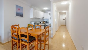 A dining area with a wooden table and chairs, a kitchen in the background, and a hallway leading to another room. - Vacation 'Candelaria 1' with Sea View, Wi-Fi and Air Conditioning (Candelaria)