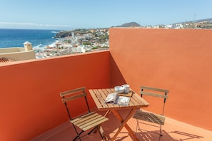 A balcony with a wooden table, two chairs, and a magazine.