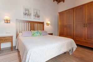 Un dormitorio con cama, armario de madera, mesitas de noche y lámparas de pared.