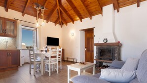 A living room with a fireplace, a dining area with a table and chairs, and a kitchen with cabinets and a TV. - Vacation Home 'Volcán 18' with Sea View, Private Terrace and Wi-Fi (El Tanque)
