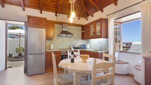 A kitchen with wooden cabinets, a refrigerator, a dining table with chairs, and a hanging light fixture. - Vacation Home 'Volcán 18' with Sea View, Private Terrace and Wi-Fi (El Tanque)