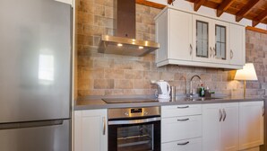 A kitchen with a stainless steel refrigerator, an oven, white cabinets, and a stone backsplash. - Vacation Home 'Volcán 16' with Private Terrace, Private Garden and Wi-Fi (El Tanque)