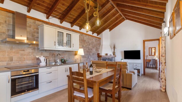 A modern kitchen with wooden cabinets, a built-in oven, and a dining area with a wooden table and chairs. - Vacation Home 'Volcán 16' with Private Terrace, Private Garden and Wi-Fi (El Tanque)