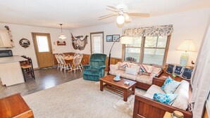 A cozy living room with a sofa, a coffee table, and a dining area with chairs and a table. - Short Walk To The Beach, Water Views, Screened in Porch, Sun Deck (Salvo)
