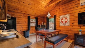 L’intérieur d’un chalet en bois comprend une cuisine, un coin repas et un téléviseur fixé au mur.